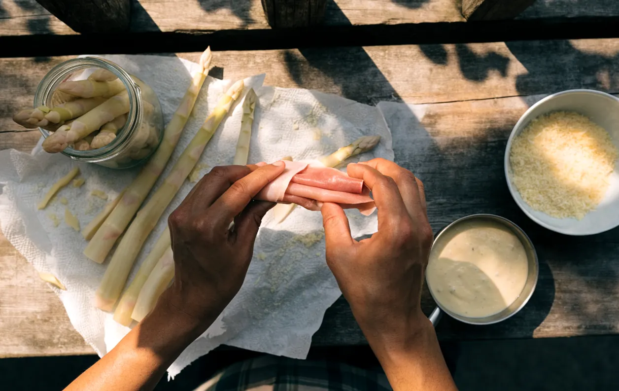 Asperges blanches en bocal égouttées puis roulées dans du jambon, vue de dessus sur une table rustique
