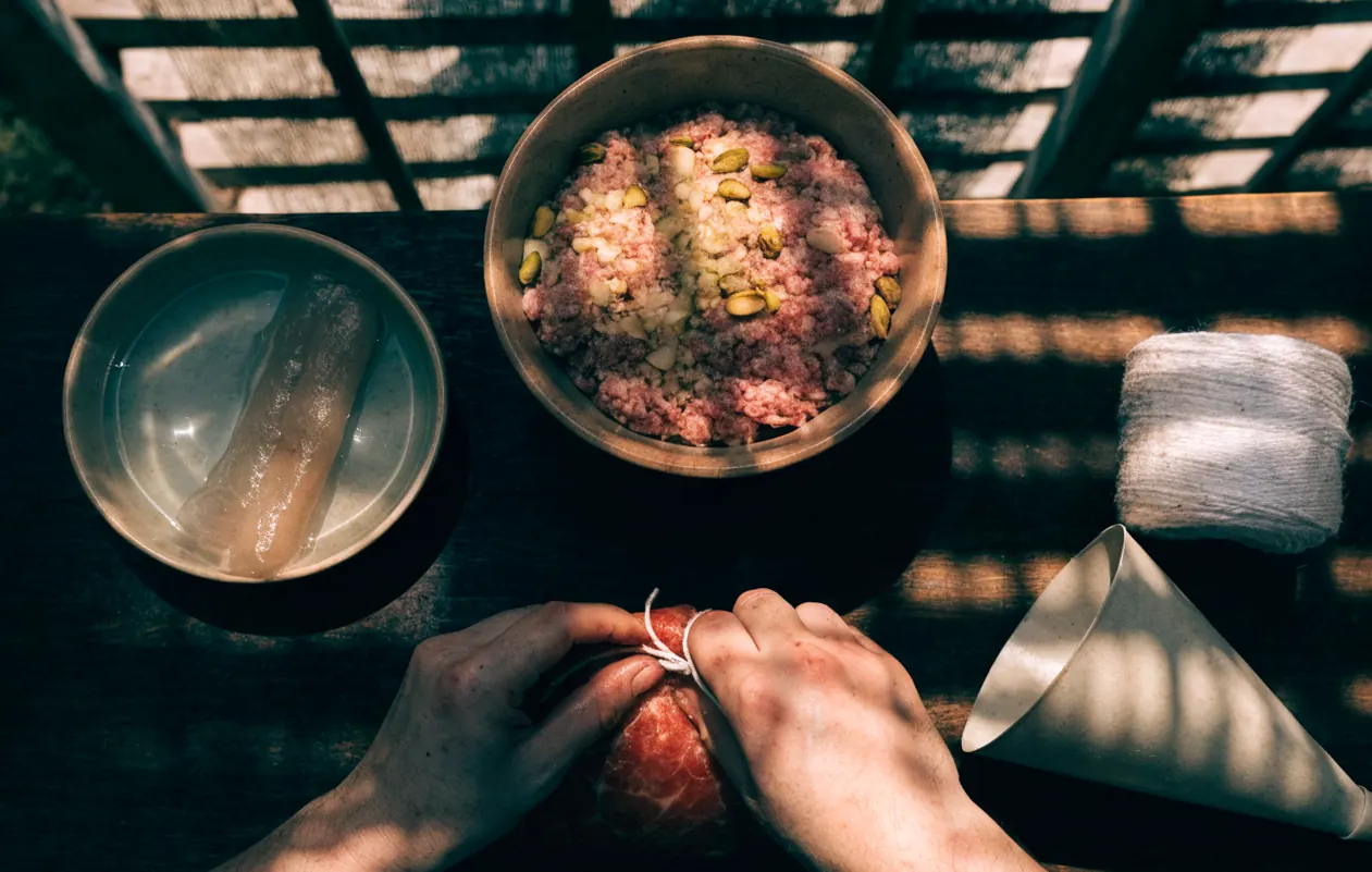 Préparation d’un saucisson maison : baudruche de bœuf réhydratée, farce de porc aux pistaches et ficelle