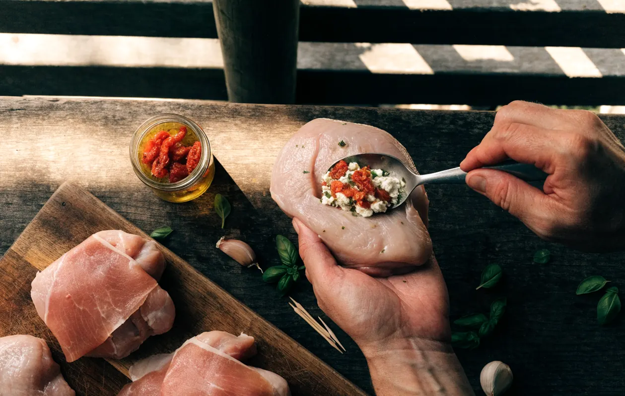 Préparation du blanc de poulet farci : poche garnie de chèvre frais, tomates séchées et basilic avant cuisson