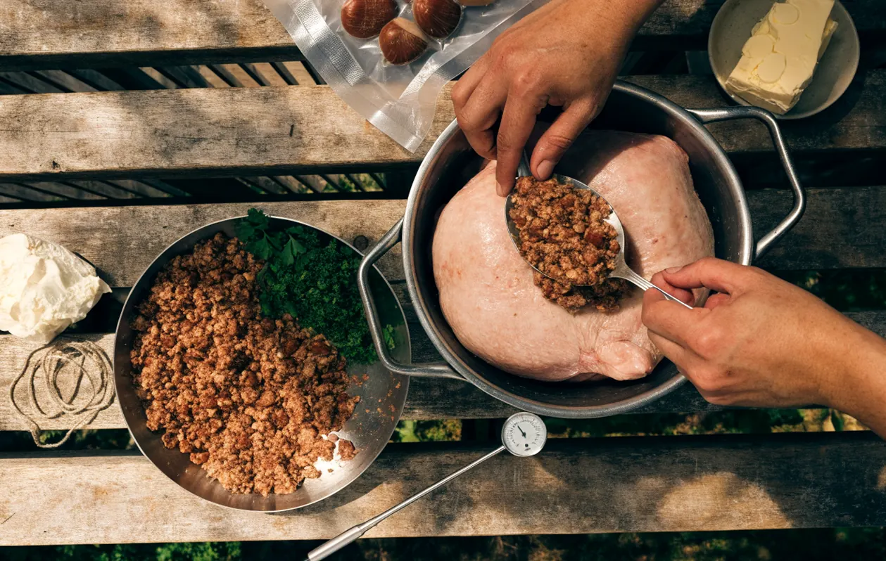 Préparation du chapon farci aux marrons : farce à la chair à saucisse et aux marrons glissée dans la volaille