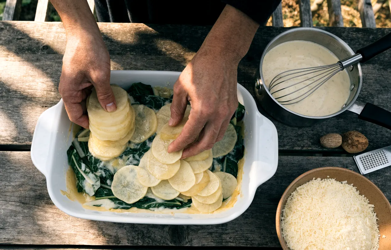 Montage du gratin de blettes et pommes de terre : couches de légumes et béchamel dans le plat
