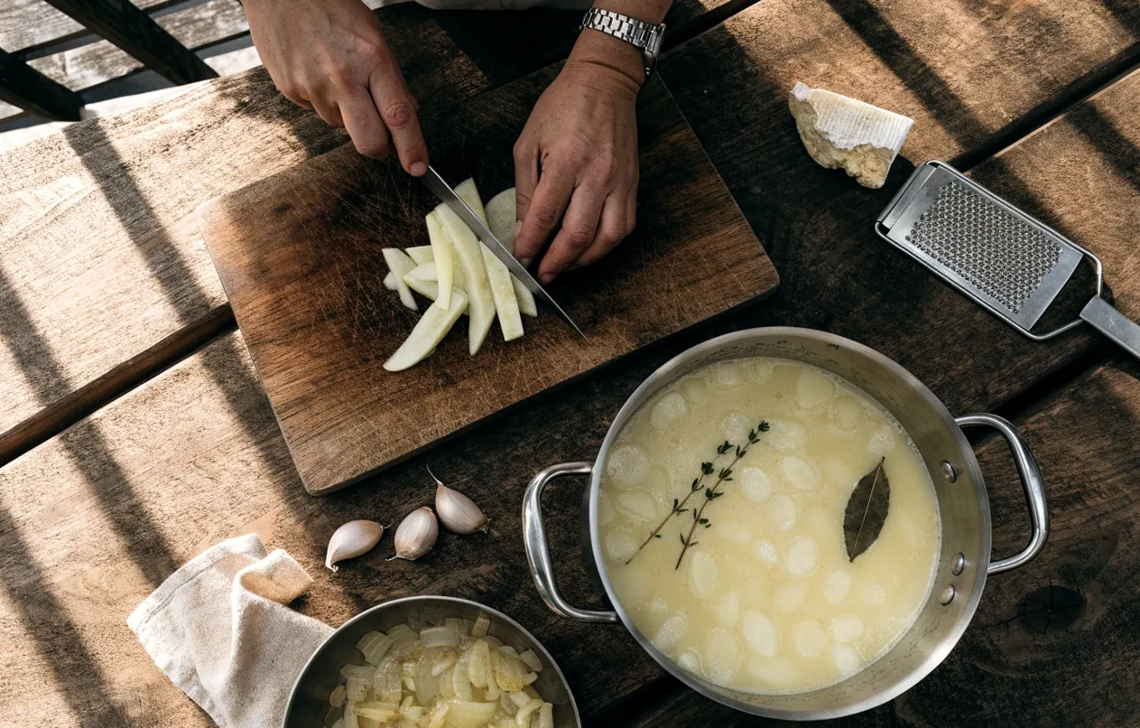 Préparation du gratin de pommes de terre du pauvre : rondelles précuites dans le lait, oignons fondus et fromage