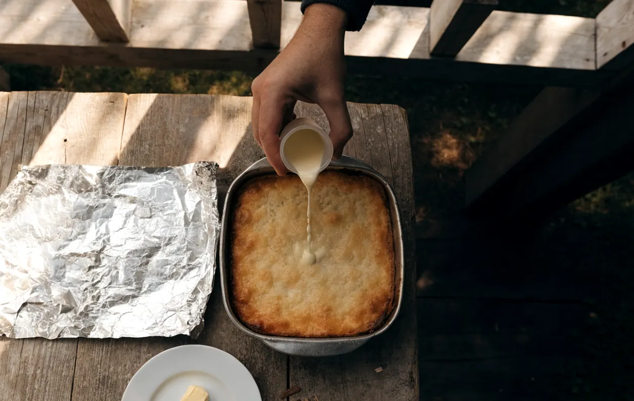 Filet de crème versé sur un gratin dauphinois froid avant de le réchauffer au four sous aluminium