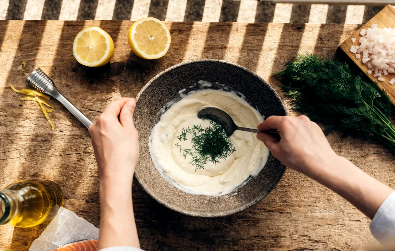Préparation de la sauce pour saumon frais : yaourt grec, aneth ciselé, zeste de citron et échalote